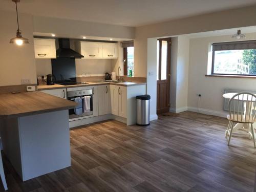 a kitchen with white cabinets and a wooden floor at Blacklaines Annexe Birdlip - Pet friendly! in Gloucester