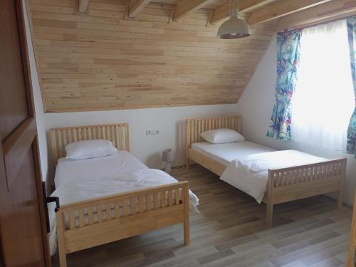 two beds in a room with wooden walls and wood floors at Bellerofon villa in Cıralı