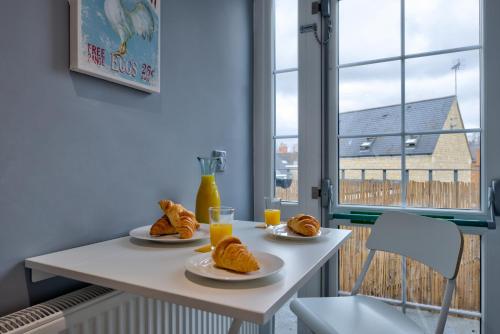 a table with two plates of croissants and orange juice at Central Stamford 2-Bed Apartment-Ideal for Work or Leisure in Stamford