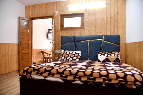 a bedroom with a large bed with a blue headboard at Samriti Apartments in Shimla