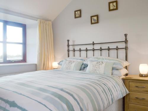 a bedroom with a large bed with pillows and a window at The Creamery in North Wootton