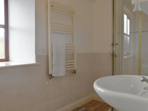 un bagno bianco con lavandino e vasca di The Creamery a North Wootton