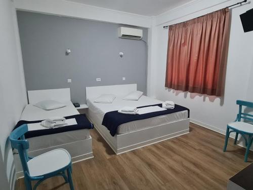 een kamer met 2 bedden, 2 stoelen en een raam bij Sparta Team Hotel in Athene