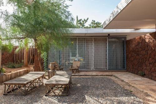 a patio with two benches and a tree at Maison Pierres in Toubab Dialaw