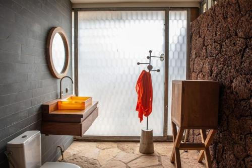 a bathroom with a sink and a toilet and a window at Maison Pierres in Toubab Dialaw