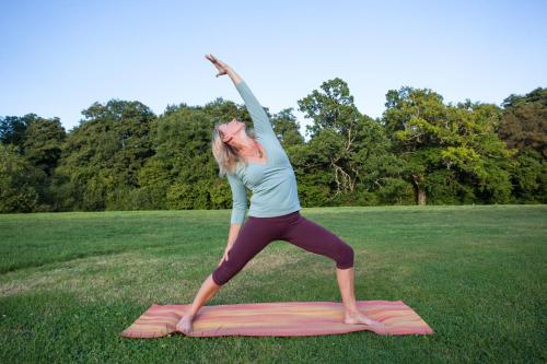 a woman doing a yoga pose on a field at Chestnut Yurt in Fernhurst