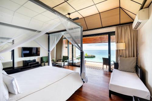 a bedroom with a white bed with a view of the ocean at Lily Beach Resort and Spa - All Inclusive in Dhangethi