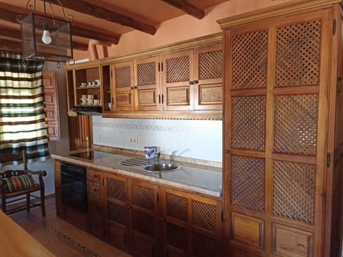 a kitchen with a sink and wooden cabinets at Apartamentos Casalpujarra in Bubión