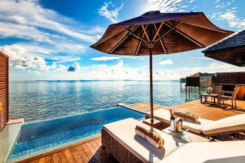 a swimming pool with an umbrella next to the water at Lily Beach Resort and Spa - All Inclusive in Dhangethi