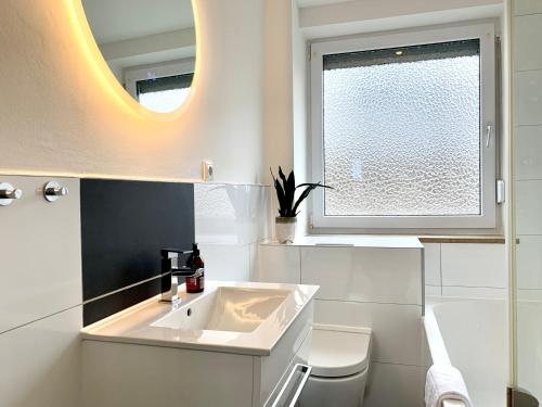 a white bathroom with a sink and a window at Antoni Homes 2-4 Personen I 2 Schlafzimmer I Messe I Uni I Arena in Augsburg