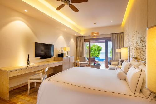 a bedroom with a bed and a desk and a television at Lily Beach Resort and Spa - All Inclusive in Dhangethi