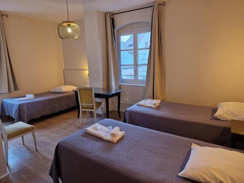 a room with two beds and a table and a window at Hôtel Patricia - Strasbourg Hyper Centre in Strasbourg