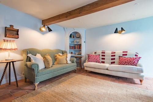 een woonkamer met 2 stoelen en een tafel bij Rogue's Cottage - Secluded gem by the sea in Deal