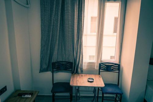 a table and chairs in a room with a window at Hotel Resat in İzmir
