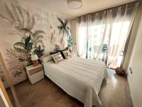 een slaapkamer met een groot bed met tropisch behang bij ACV - Vila d´Orpesa X-1ªlinea planta 4 Norte in El Borseral