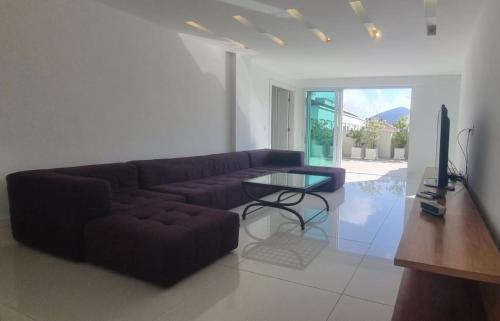 a living room with a couch and a glass table at Cobertura COM PISCINA in Rio de Janeiro