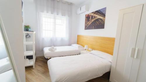 Habitación pequeña con 2 camas y ventana en RentalSevilla Disfruta por San Leandro en un alojamiento con 3 habitaciones en Sevilla