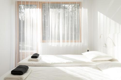 - une chambre blanche avec 2 lits blancs et une fenêtre dans l'établissement manō, à Barlinek