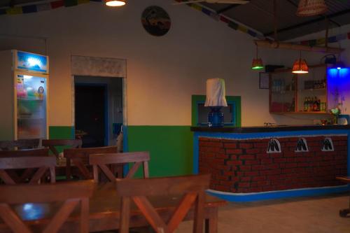 a restaurant with a bar and wooden tables and chairs at Bamby Chilling House in Sauraha