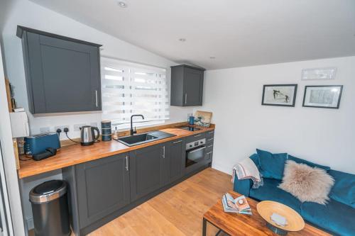 a kitchen with a blue couch in a room at Lakeside Lodge- 'Swallow' in Bishampton