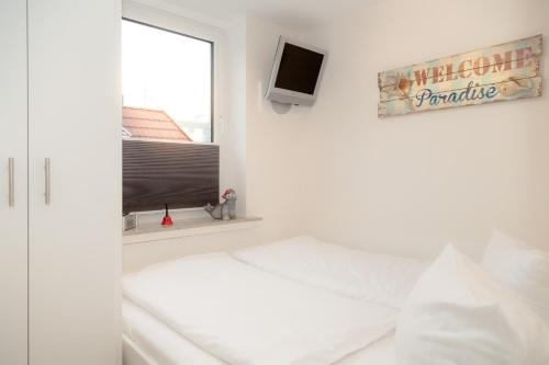 um quarto branco com uma cama e uma janela em Boy5 12 Boysens5 em Westerland