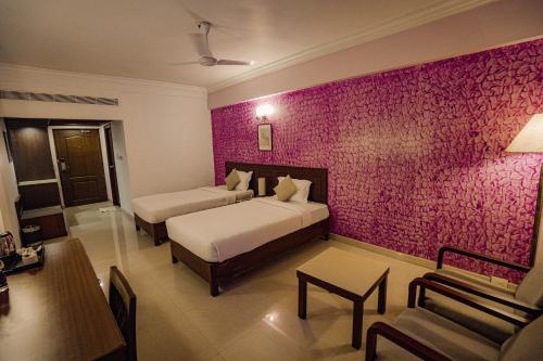 a bedroom with two beds and a pink wall at Casino Hotels Ltd in Trichūr