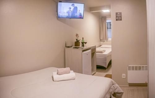 um quarto com uma cama e uma televisão na parede em Hospedagem Vila Suiça Centro em Gramado