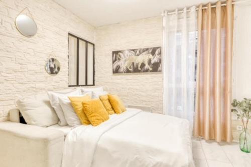 um quarto com uma grande cama branca com almofadas amarelas em Le cosy DisneyLand Paris em Montévrain