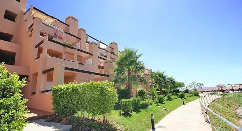 un edificio con palmeras frente a una acera en Casa Leona: Fully furnished, secure golf resort penthouse apartment with gorgeous views in Murcia en Murcia