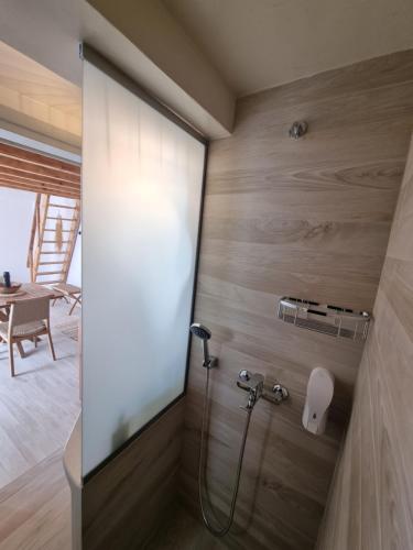 a shower in a bathroom with wooden walls at Lovely House at Oia Village Center in Oia