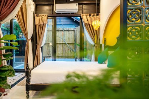 una camera da letto con un letto e una finestra di Hoi An Oasis Rosie Villa - 1 Bedroom with Private Pool and Garden View, Local Hoi An Decor a Hoi An