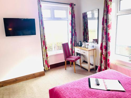 a bedroom with a pink bed and a desk and window at The Railway Inn in Rise