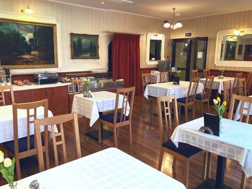 a restaurant with white tables and chairs and a kitchen at Liza Aqua & Conference Hotel in Lajosmizse