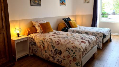 a bedroom with two beds and a lamp on a table at Gîte de l'Aff in La Gacilly