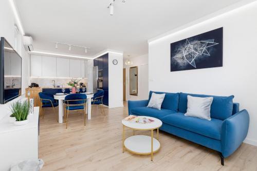 a living room with a blue couch and a kitchen at Fredry 6 Apartment Premium Łagiewniki by Renters Prestige in Kraków