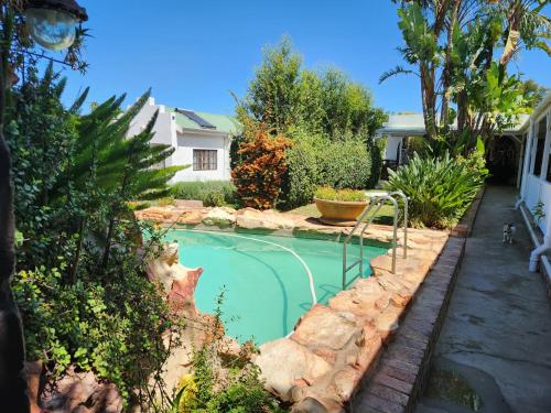 a small swimming pool in a yard with rocks at Best Little Guesthouse -Beit Shalom in Oudtshoorn