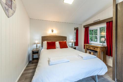 a bedroom with a large white bed with red pillows at FAIRVIEW FARM Holiday Accommodation 14 Luxury Lodges, Cabins, Dog Friendly, Suitable for Couples, Families and Groups, Wedding Guests , Corporate events, Sleeps 2-65 guests in Ravenshead, Nottingham near Sherwood Forest, set in 88 acres in Nottingham