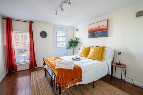 a bedroom with a bed with white sheets and yellow pillows at Cozy Townhouse Downtown w/ Game Room & Rooftop in Baltimore