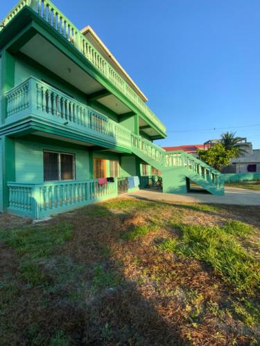 un edificio verde con balcón y patio en Hostel Casa Verde, Tela Atlantida., en Tela