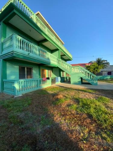a green building with a balcony and a yard at Hostel Casa Verde, Tela Atlantida. in Tela