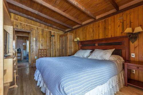 a bedroom with a bed and a wooden wall at Cabañas Mapulay in Pucón
