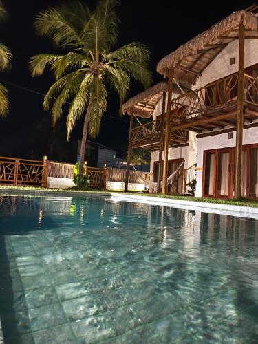 a swimming pool in front of a house with a palm tree at Casa di Maria flats in Icaraí