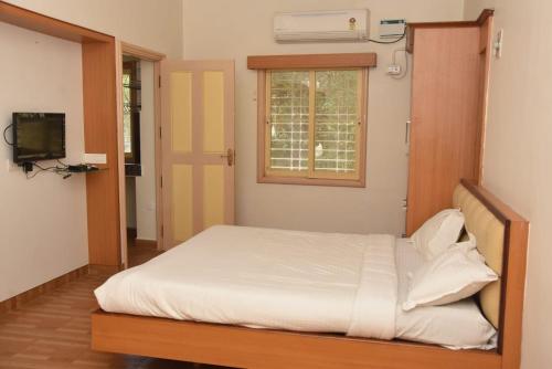 um quarto com uma cama, uma janela e uma televisão em arulmigu sivasakthi siddhar peedam garden guest house em Tiruvannamalai