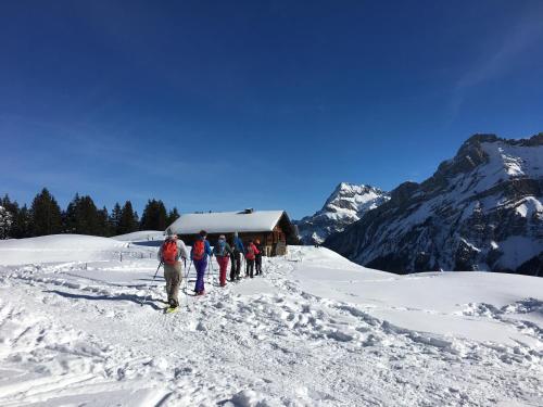 a group of people walking in the snow near a cabin at ERMITAGE Wellness- & Spa-Hotel in Gstaad