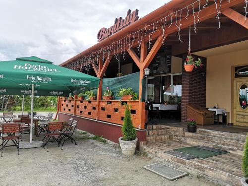 ein Restaurant mit Tischen, Stühlen und einem Sonnenschirm in der Unterkunft Barátság Panzió - Pensiunea Barátság in Ditrău