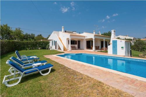 a pair of blue lounge chairs next to a swimming pool at Villa Alegria in Loulé