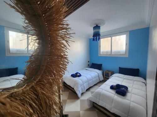 two beds in a room with blue walls and windows at Green Surf House in Agadir