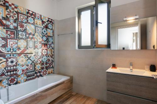 een badkamer met een bad, een wastafel en een spiegel bij Villa Elia in Maroulás