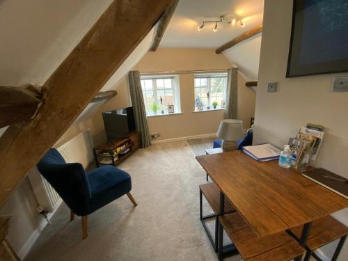 Una sala de estar con una mesa de madera y un televisor. en Stable Lodge at Bledington Mill, en Bledington