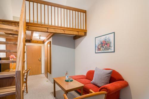 a living room with a red couch and a table at Romantischer Seegasthof & Hotel Altes Zollhaus in Feldberg